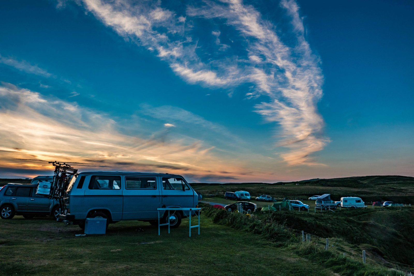 taiki-ishikawa-w6EMxsk8CDA-unsplash A scenic sunset view of Volkswagen campervans parked in Durness, Scotland.