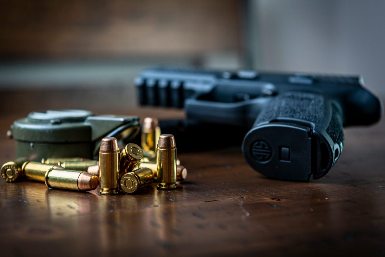 taiki-ishikawa-w6EMxsk8CDA-unsplash Close view of a handgun with bullets on a wooden surface, emphasizing firearms and ammunition.