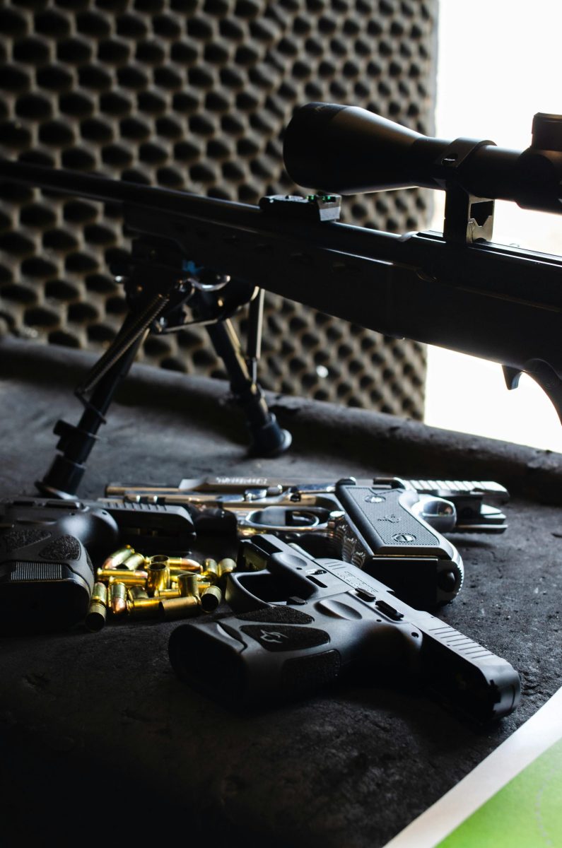 Close-up of various firearms and ammunition on a shooting range table in São Paulo, Brazil.
