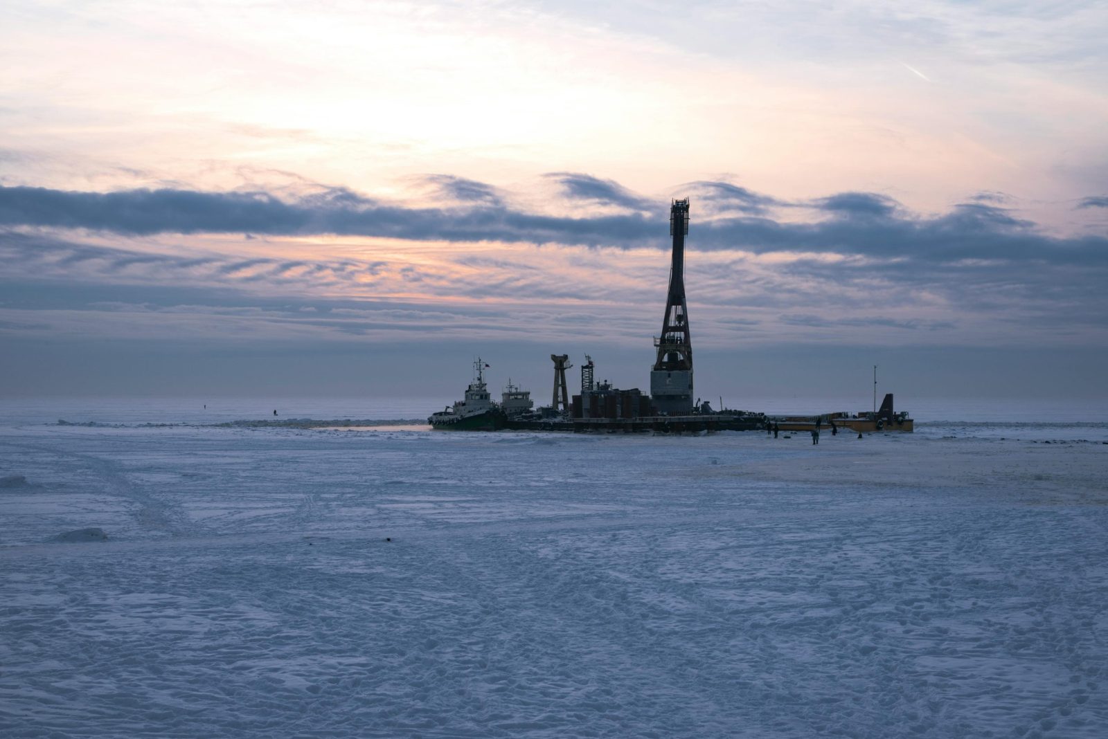 Scenic view of an offshore oil platform on a frozen sea during sunset, capturing the serene winter landscape.