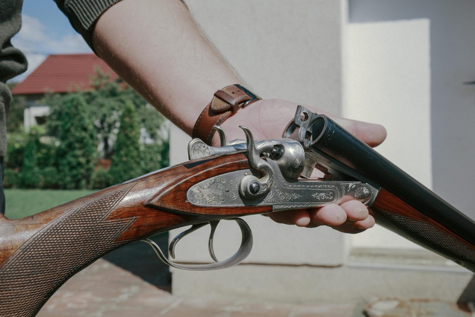 Close-up of a handcrafted double barrel shotgun showcasing intricate metal engravings and walnut wood.