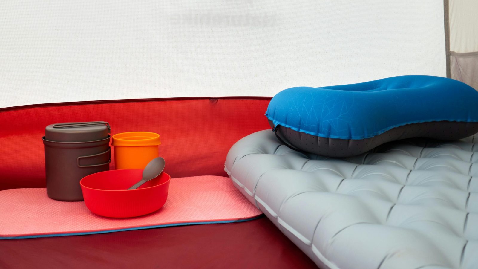 Inside a tent with inflatable pillow, cookware, and sleeping pad, ideal for camping.