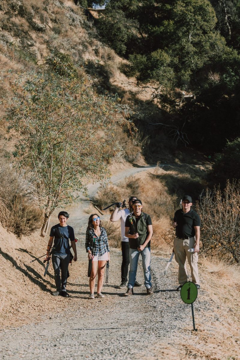 A group of adults engaging in archery during a hiking trip in nature.