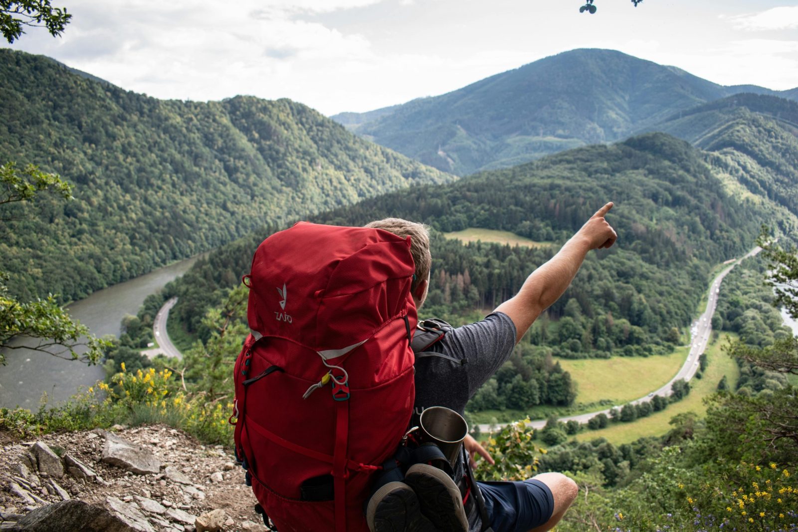 A backpacker points to a stunning mountain view in Slovakia, capturing the adventurous spirit of exploring the great outdoors.