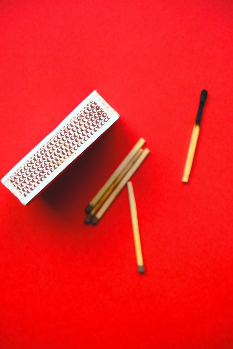 A top view of a matchbox and matches arranged on a vibrant red background.
