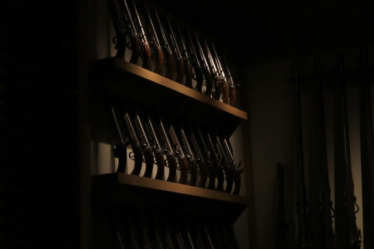 a shelf filled with lots of guns in a dark room