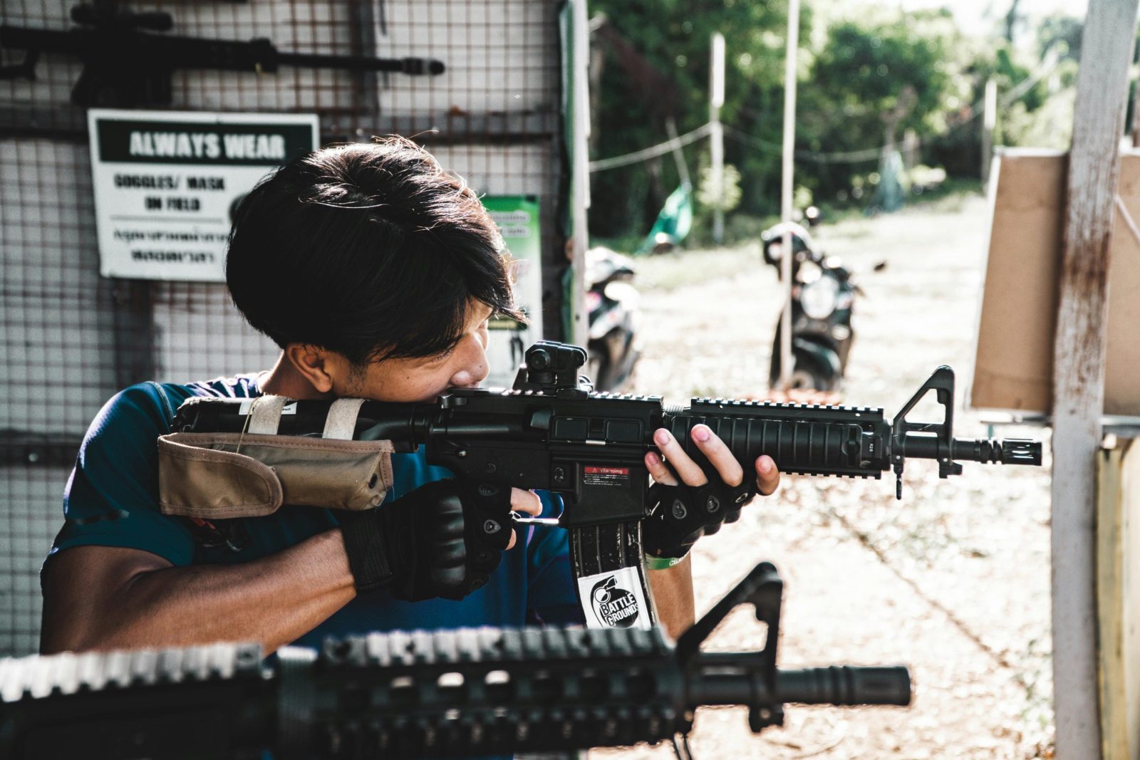 A man aiming a rifle at an outdoor shooting range, focusing intently.