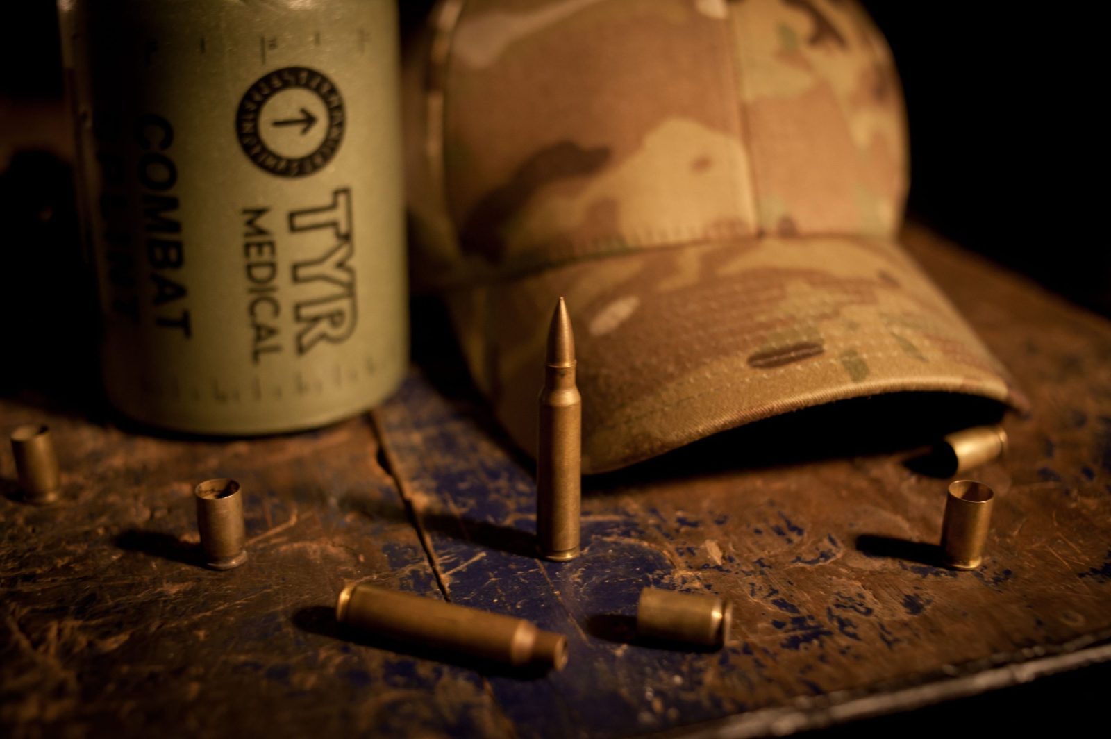 Camouflage cap and combat ammunition on rustic surface.